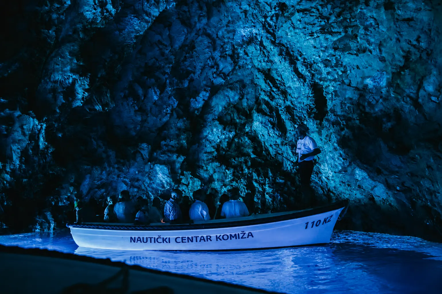 Speedboat inside the Blue Cave on Bisevo island with sunlight glowing electric blue through the water