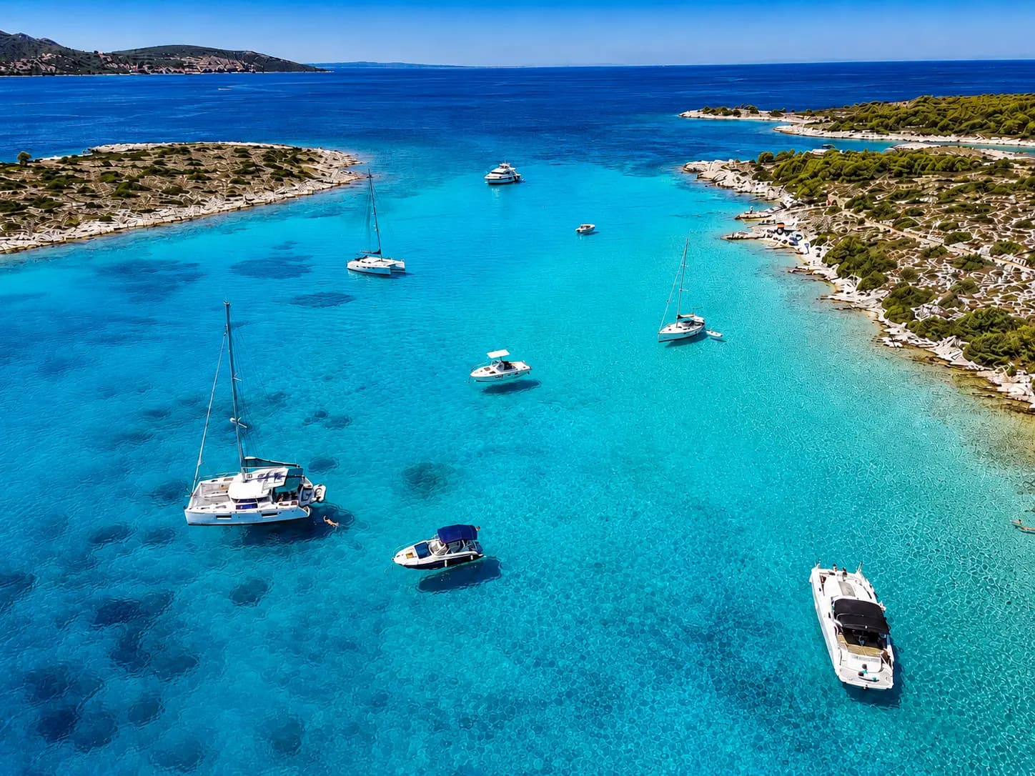 Shallow turquoise water of the Blue Lagoon at Krknjaši Bay with boats anchored off Drvenik Veli