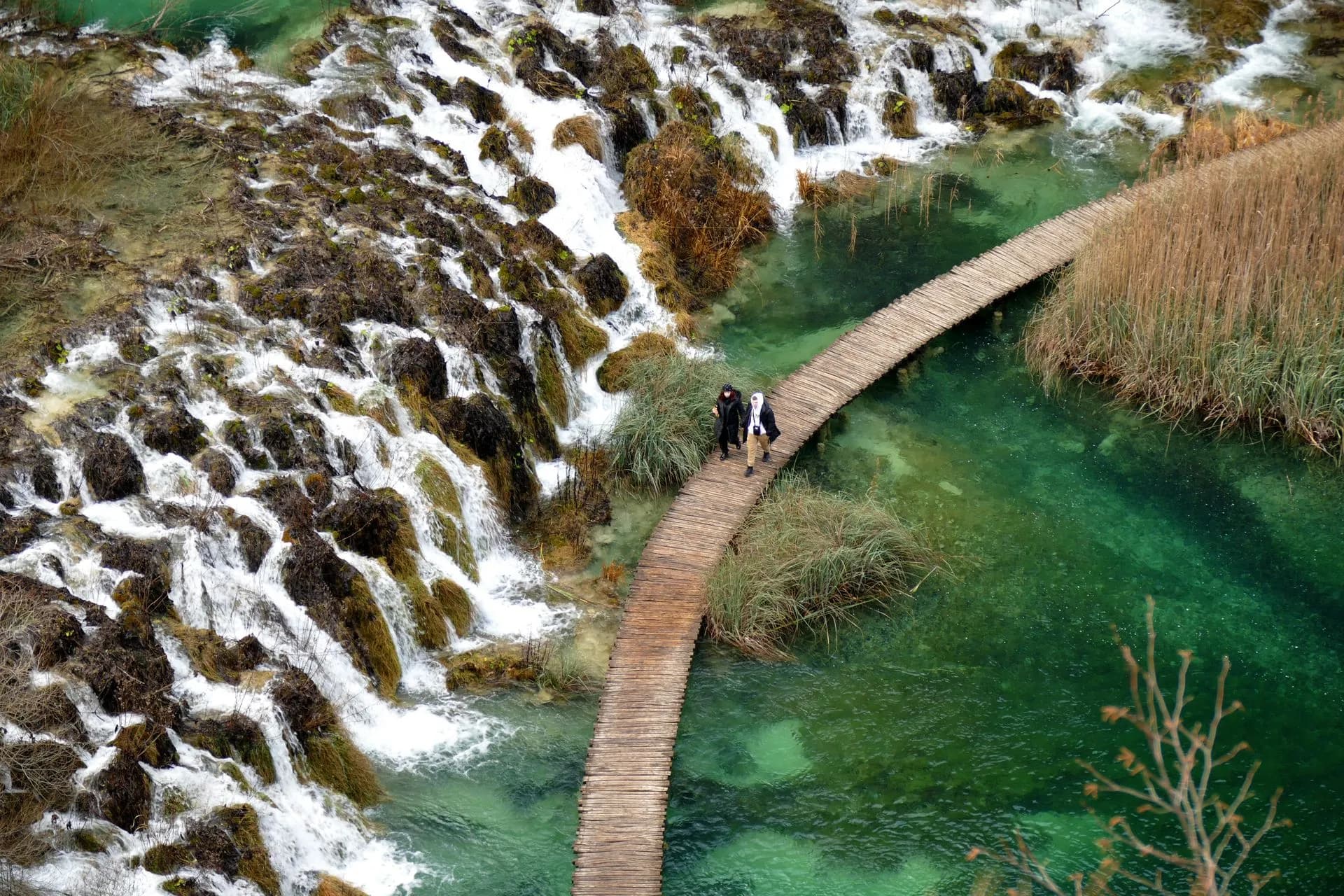 Wooden boardwalk winding between turquoise lakes and waterfalls at Plitvice Lakes National Park