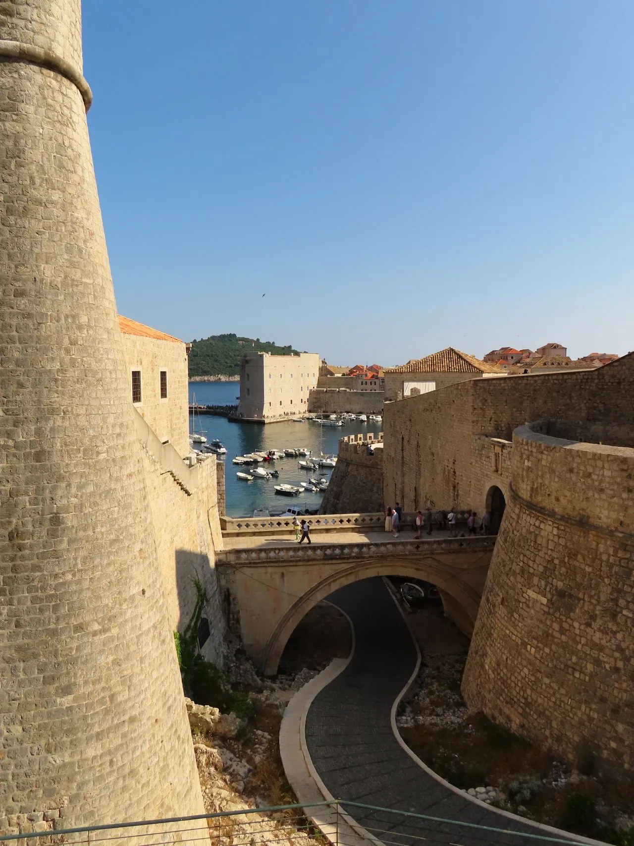 Dubrovnik's medieval stone city walls curving above the marina and terracotta rooftops